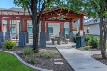 A covered outdoor seating area with a table and chairs at Roosevelt Commons Apartments, Phoenix